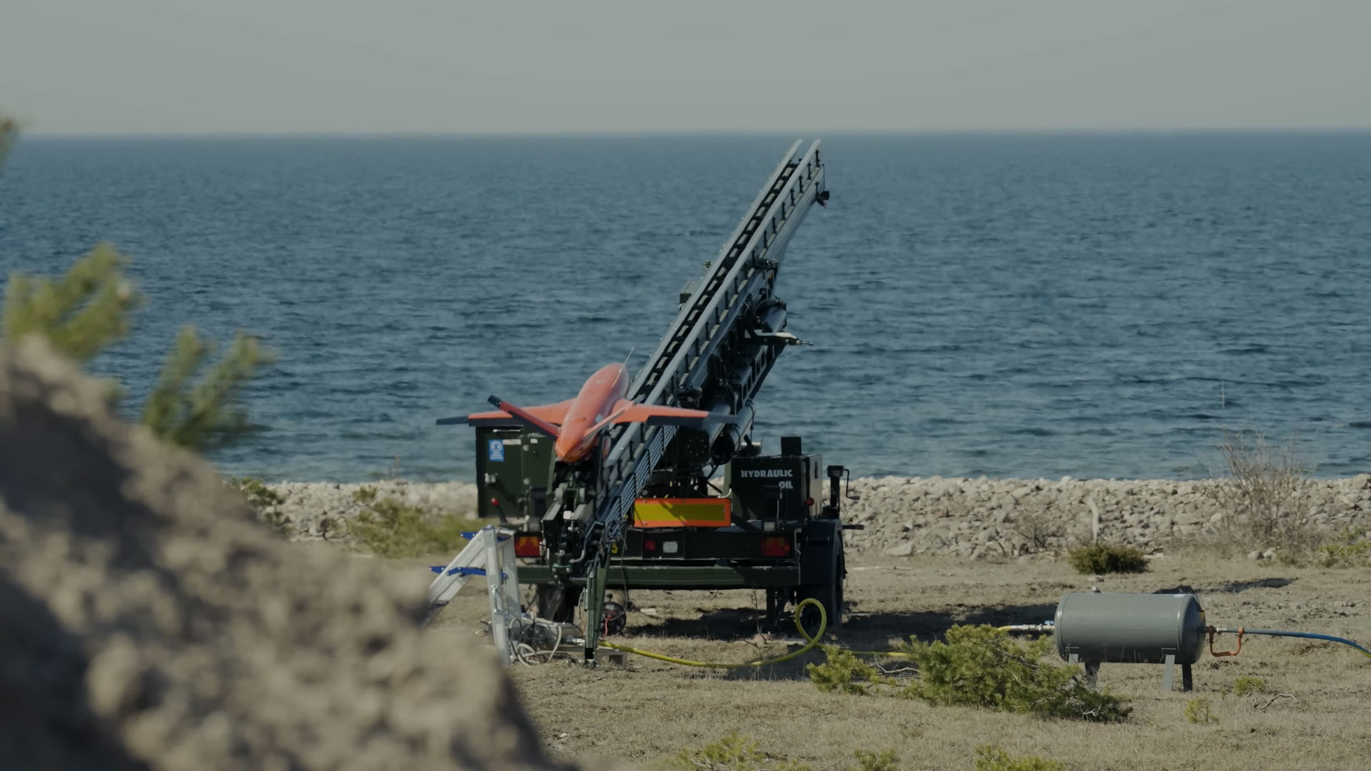 En avfyrningsramp som avfyrar en orange målrobot ut över havet.