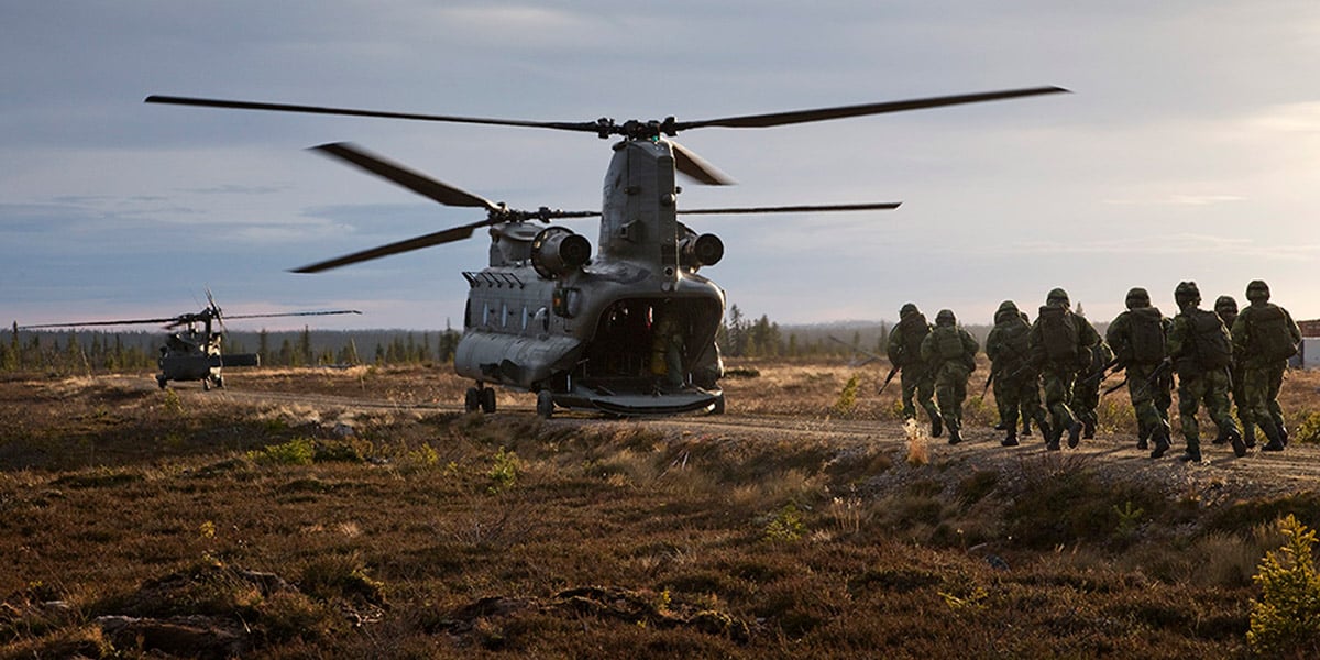 A group of soldiers moving towards a helicopter on the ground