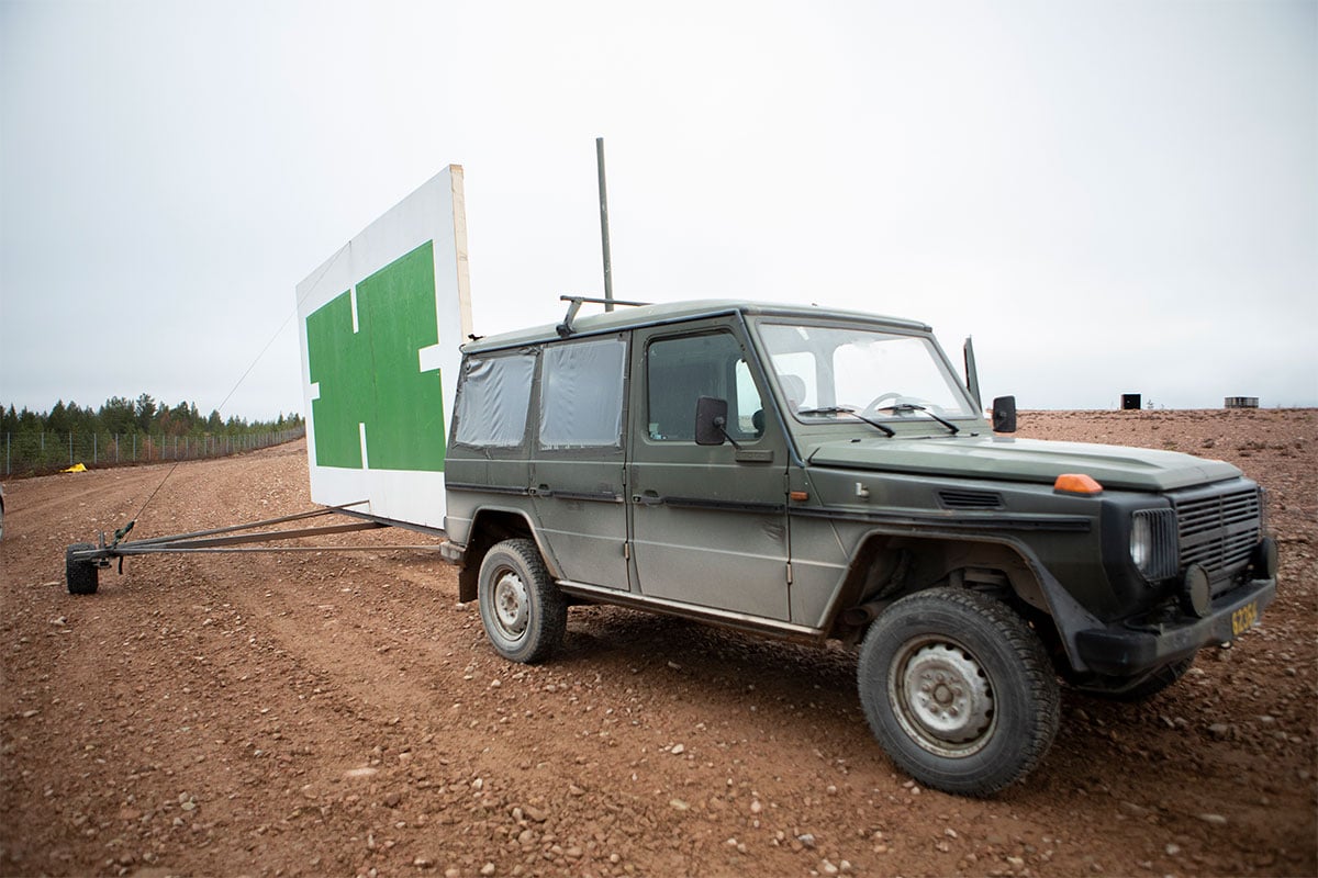 A SUV with a large shield in tow as remotely controlled moving target