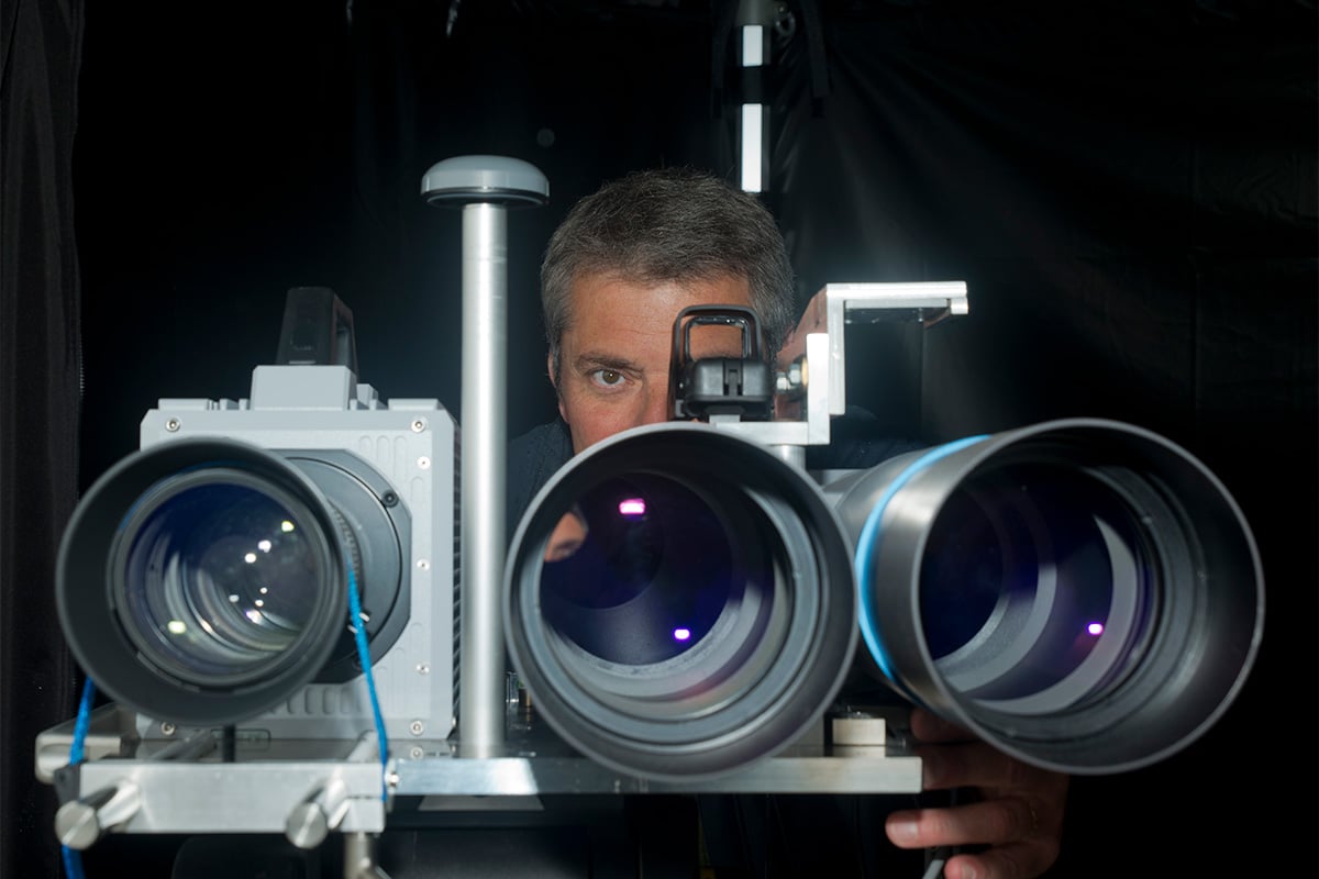 A man behind three parallel camera obejctives